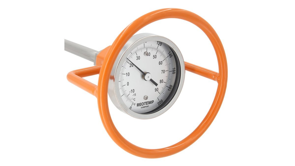 Compost thermometer probe inserted into dark compost inside a wooden bin