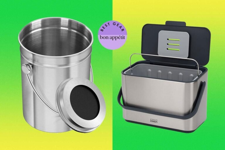 Stainless steel kitchen compost bucket on a wooden countertop beside vegetable scraps